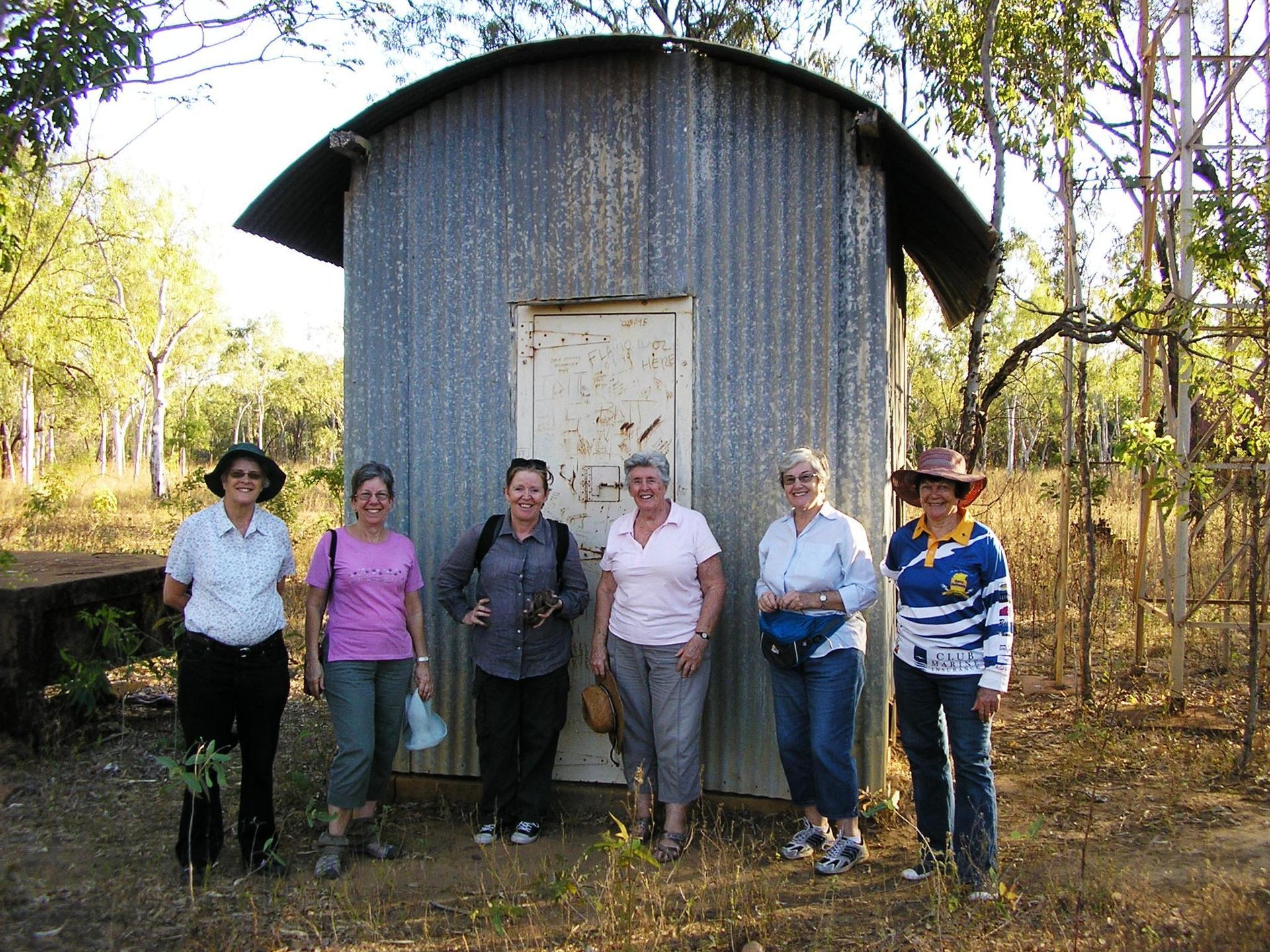 A group of women standing in front of a small building