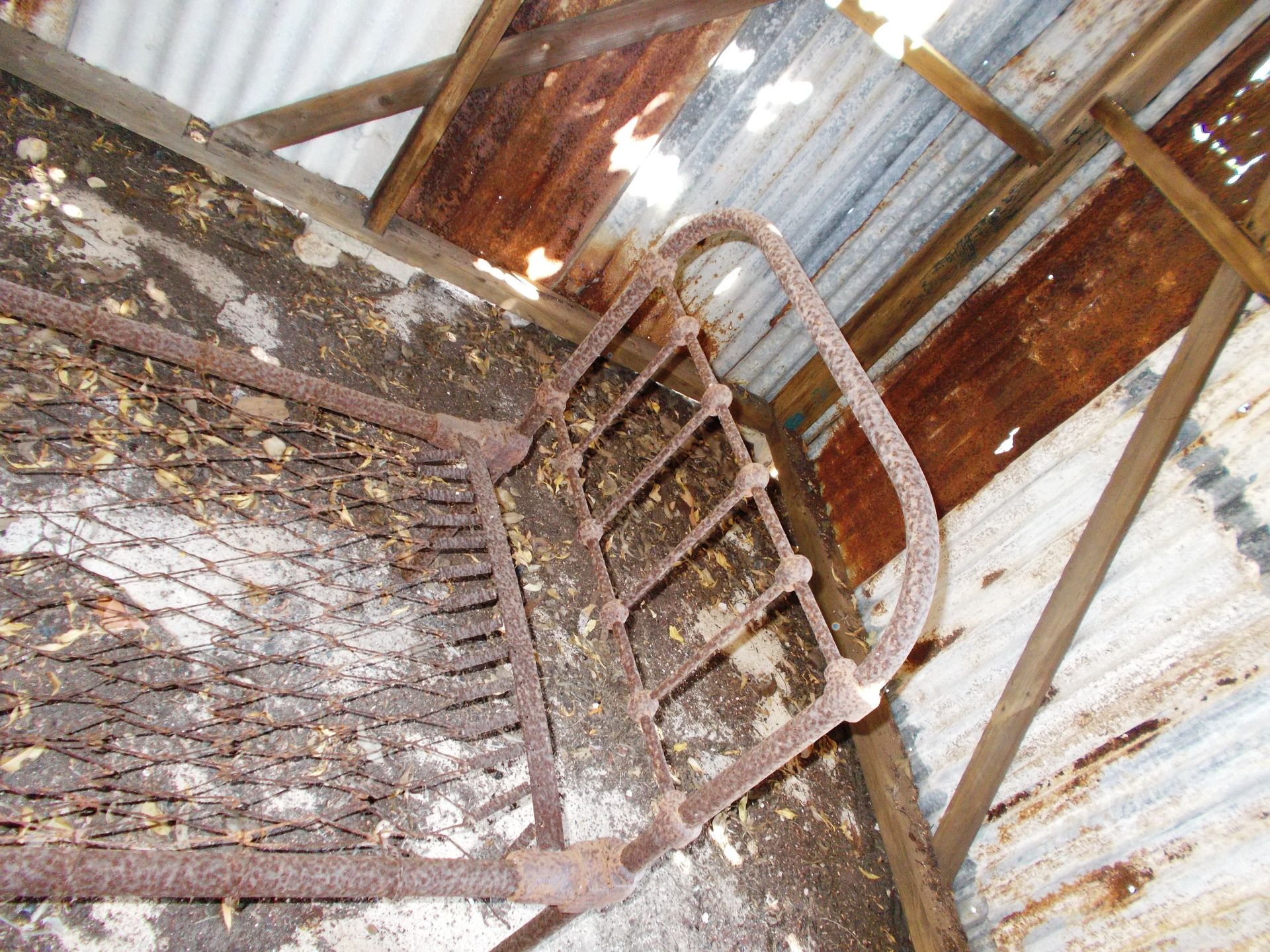 A rusty metal staircase with a metal roof in the background
