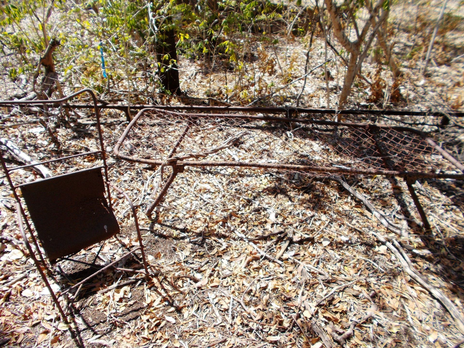 A rusty metal structure is sitting on the ground in the woods.