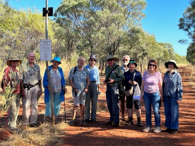 A group of people standing next to each other on a dirt road.