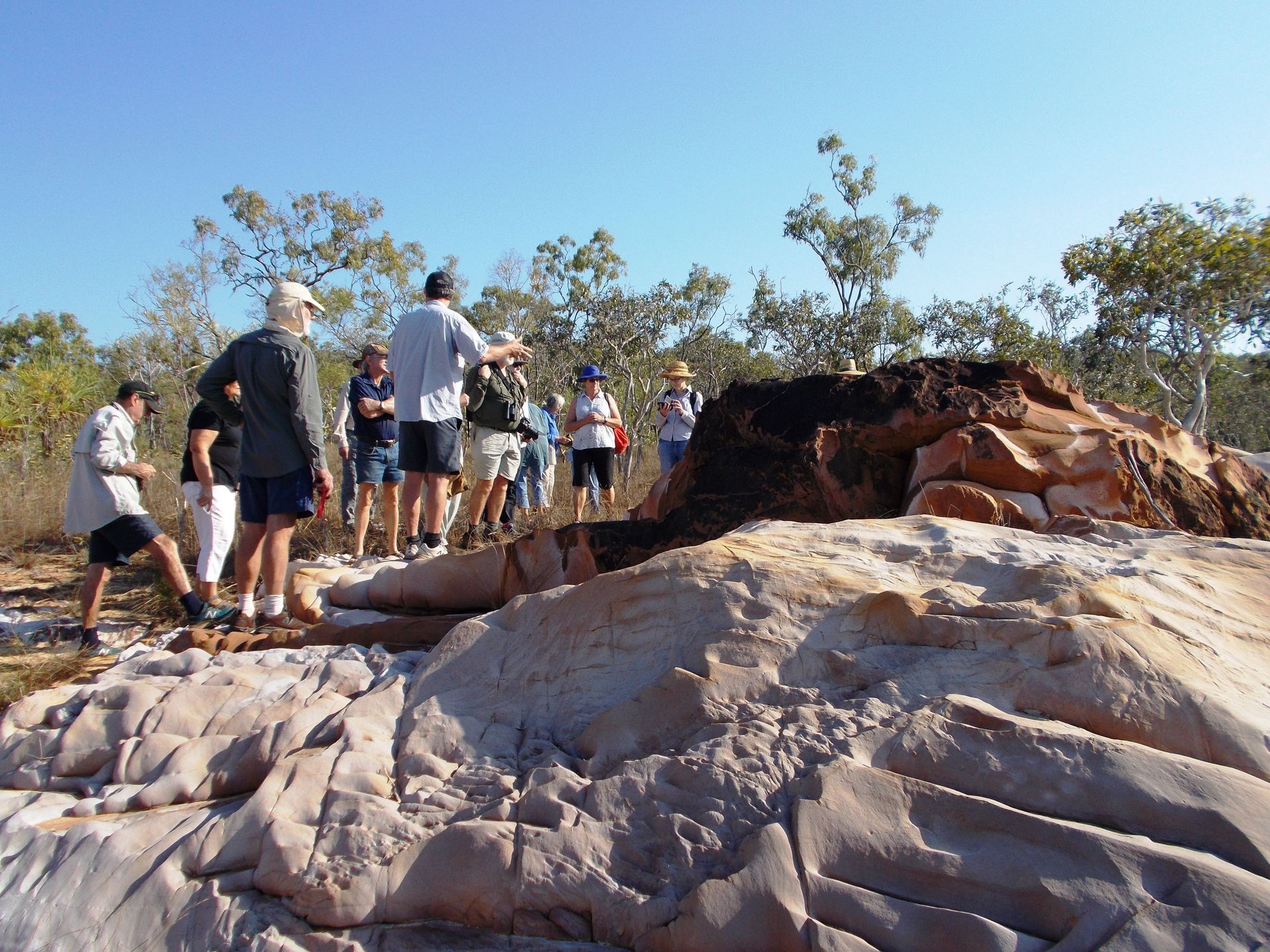 A group of people standing on top of a large rock