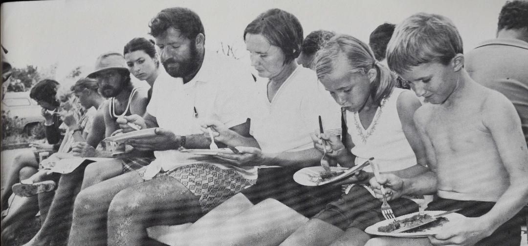 A group of people are sitting in a row eating food.