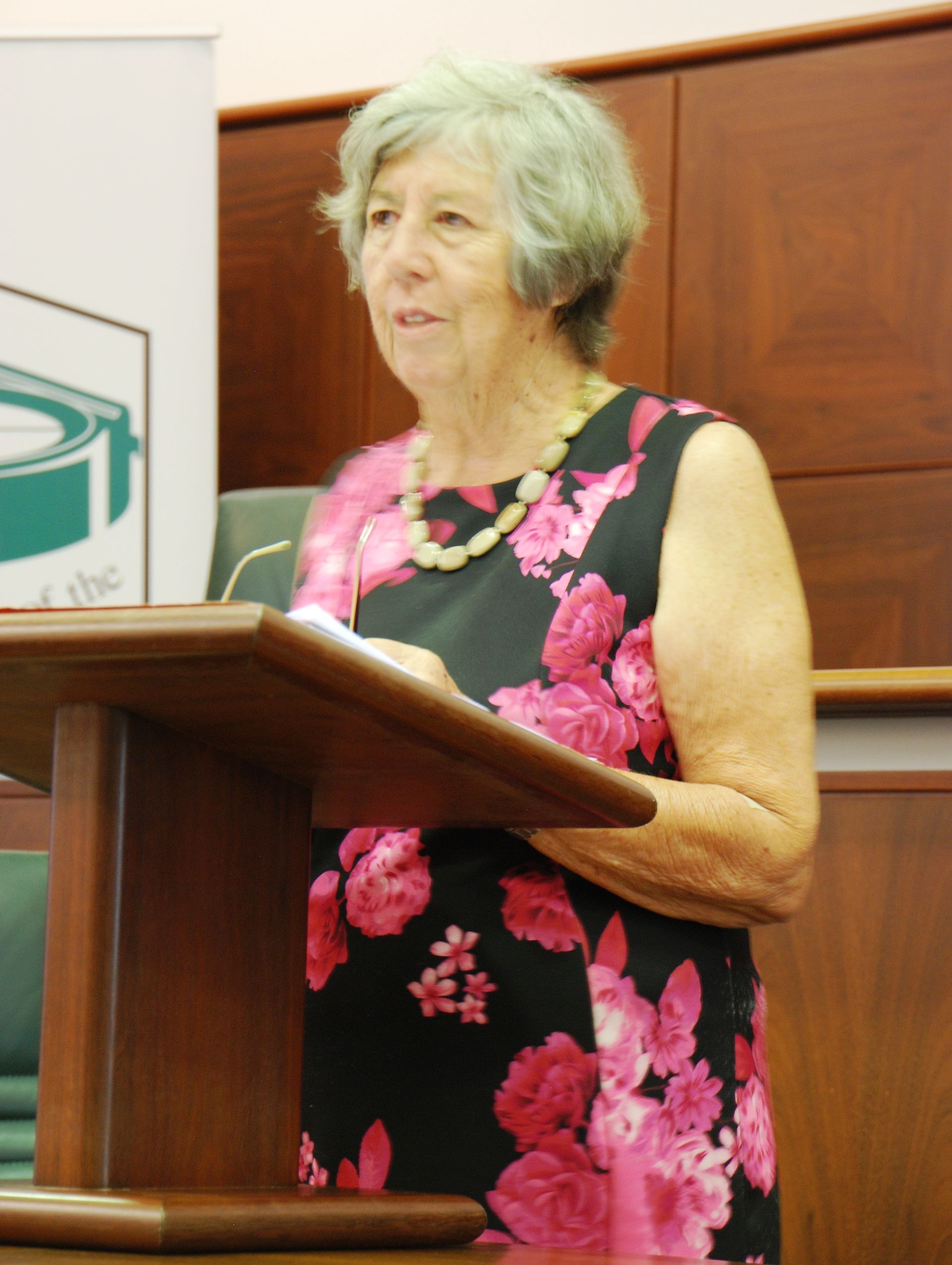 A woman in a floral dress stands at a podium