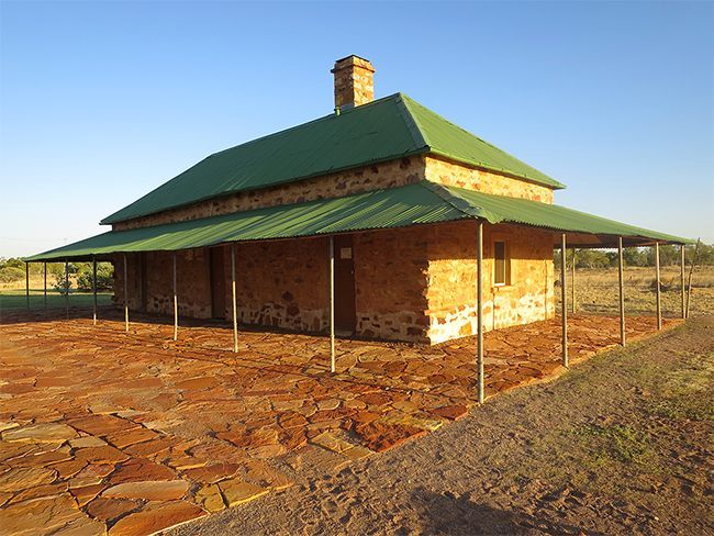 A stone house with a green roof and a porch
