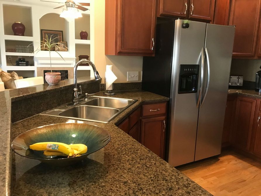 A kitchen with two sinks and a stainless steel refrigerator