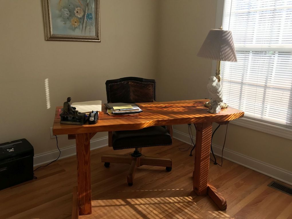 A wooden desk with a chair and a lamp in a room.