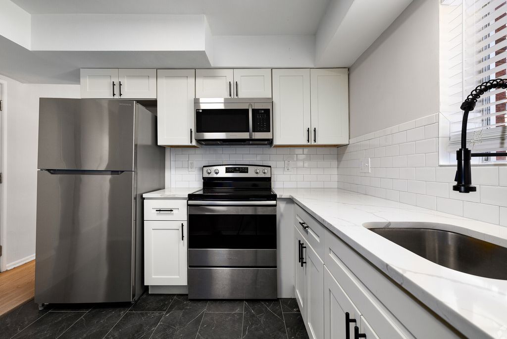 A kitchen with stainless steel appliances and white cabinets