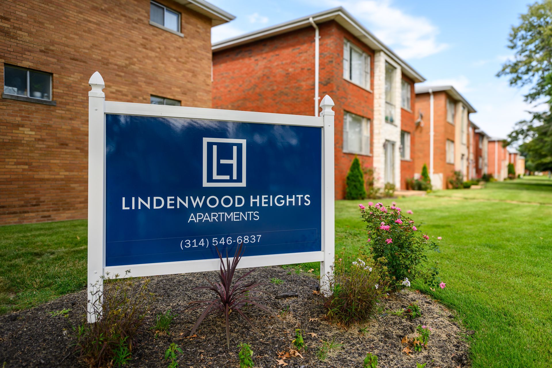 A sign for lindenwood heights apartments is in front of a brick building.