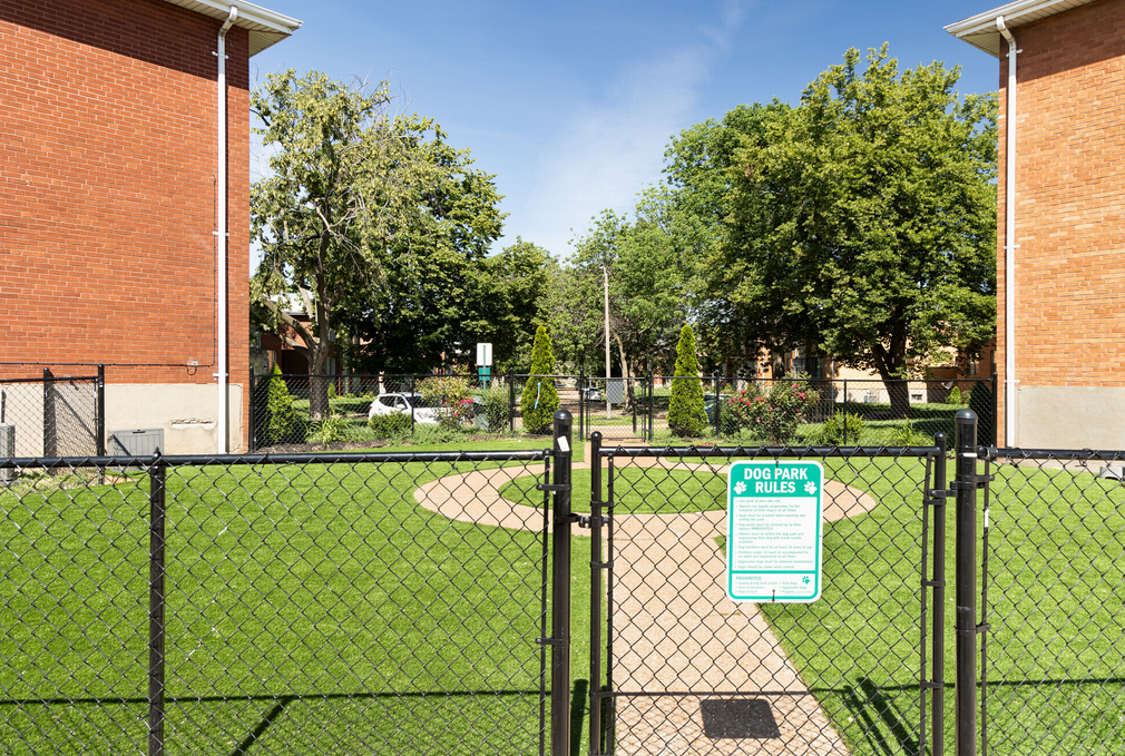 A chain link fence surrounds a park with a sign on it.