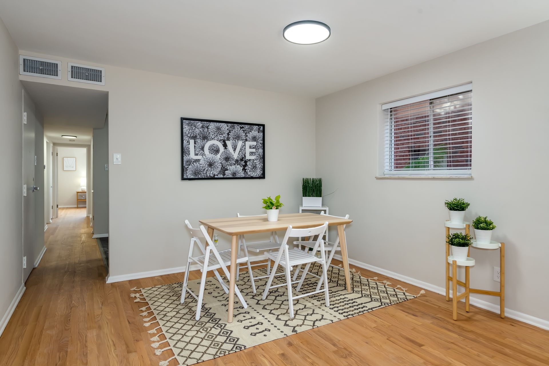 A dining room with a table and chairs and a picture on the wall that says love.