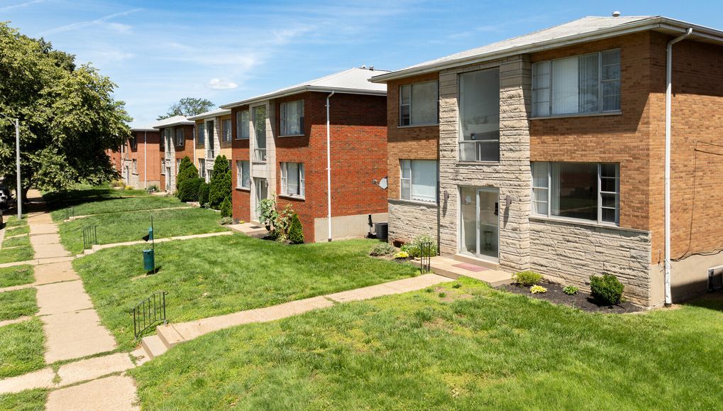 A row of apartment buildings sitting next to each other on a lush green lawn.