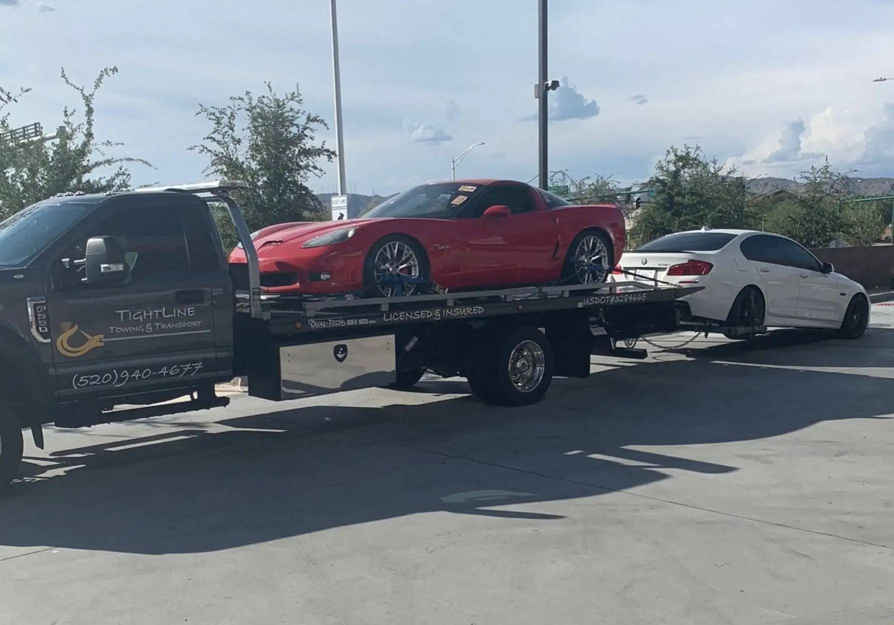 A red Corvette and white sedan being towed on a flatbed truck.