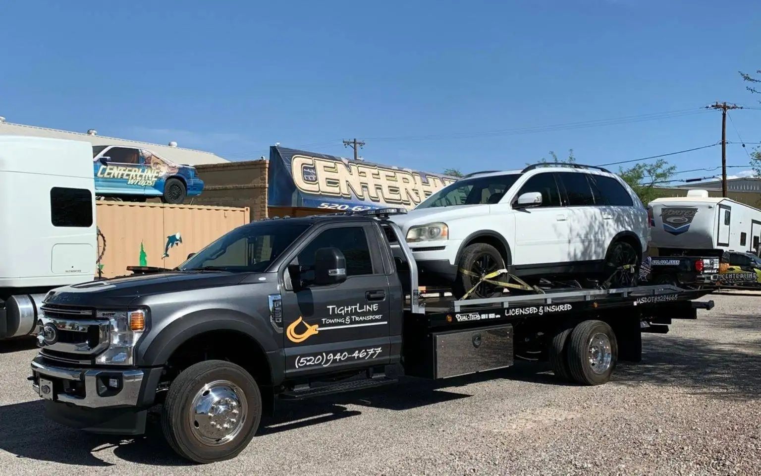 Tow truck with a white SUV, parked outdoors on a sunny day.