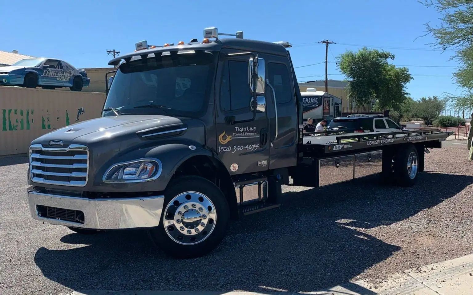 Dark gray tow truck parked outside on a sunny day.