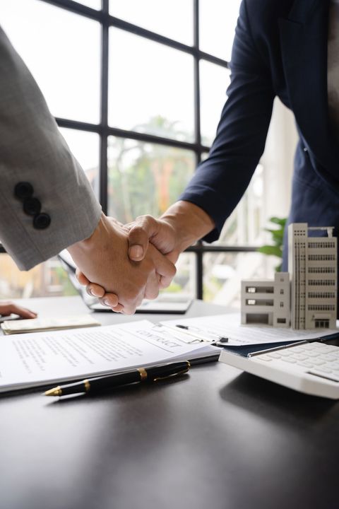 A man and a woman are shaking hands over a table.