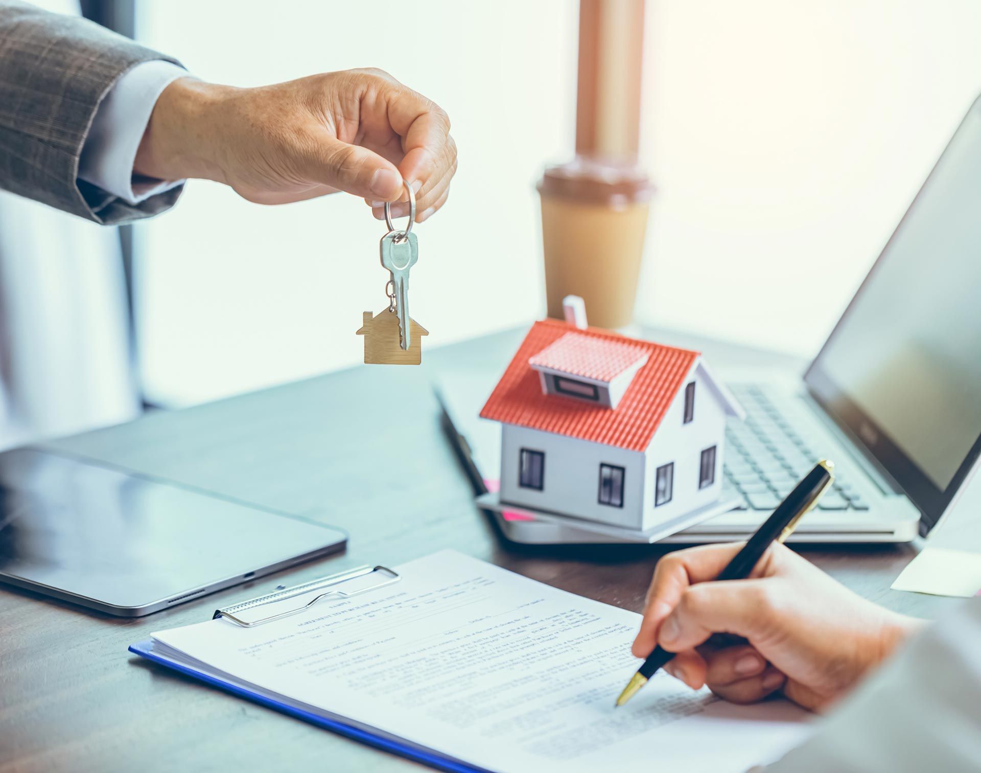 A man is giving a key to a woman who is signing a contract.