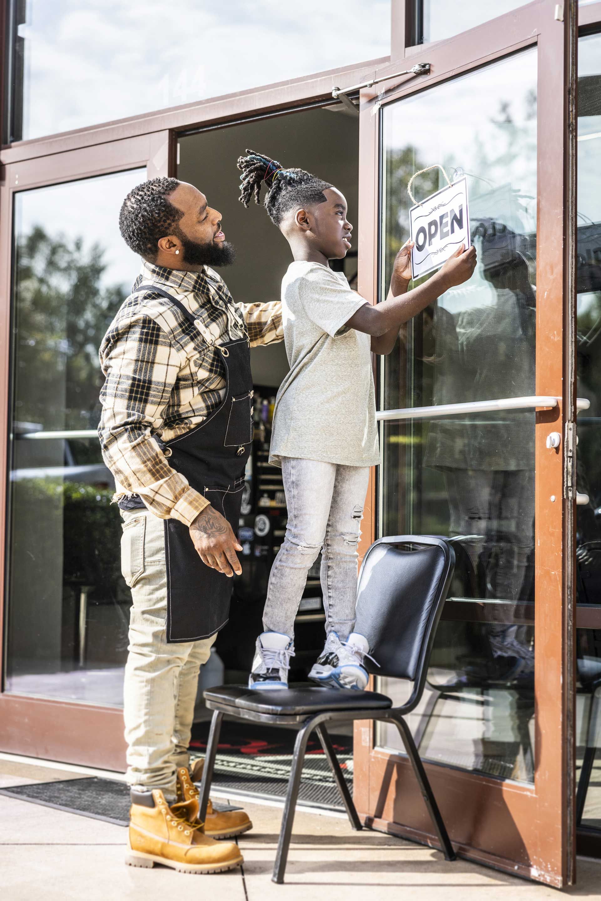 A man and a child are standing in front of a glass door.