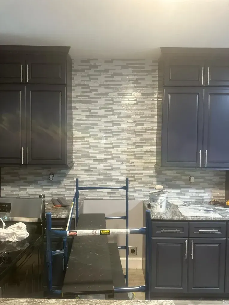 Kitchen with a tiled backsplash, dark blue cabinets, and scaffolding.