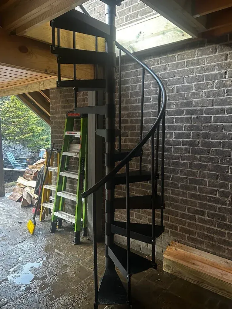 A spiral staircase is being built in front of a brick wall.