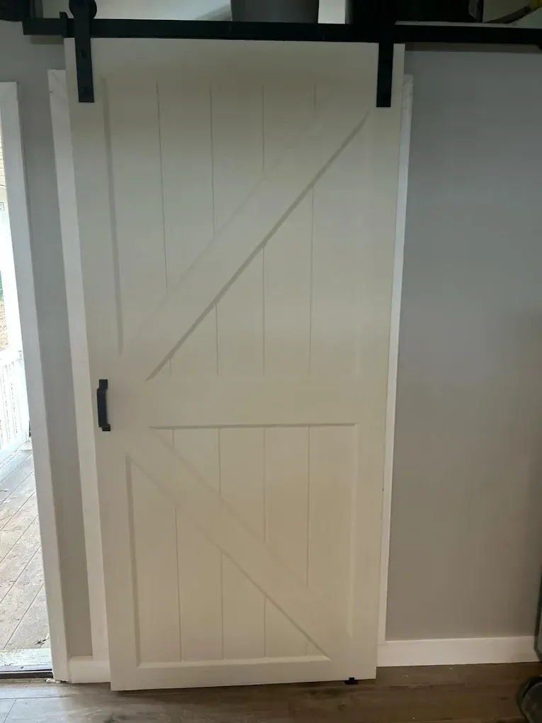 A white sliding barn door is hanging on a wall in a room.