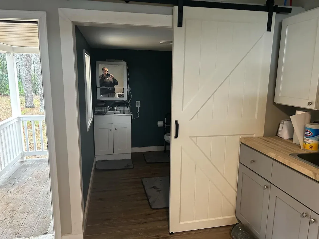 Bathroom doorway with sliding barn door, leading to a small bathroom with dark green walls and a vanity.