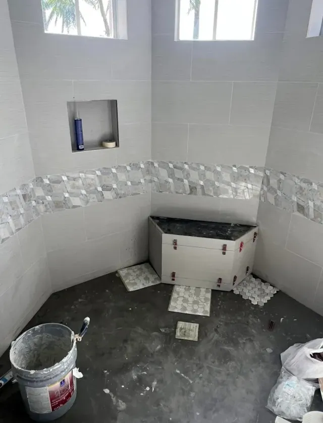 A bathroom under construction with a bucket of concrete on the floor.