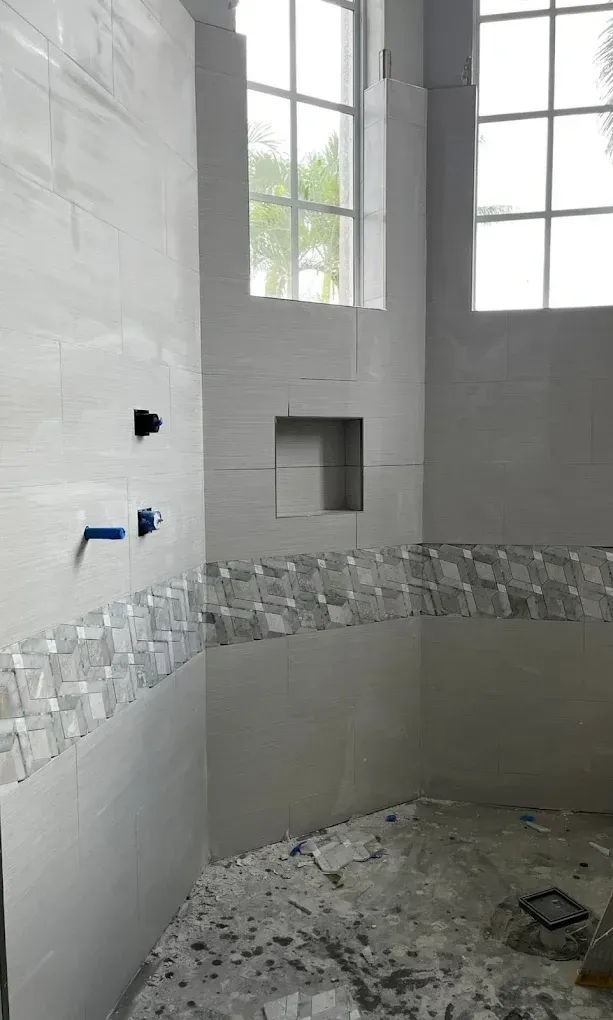 Bathroom under construction with light gray tile and mosaic accents.