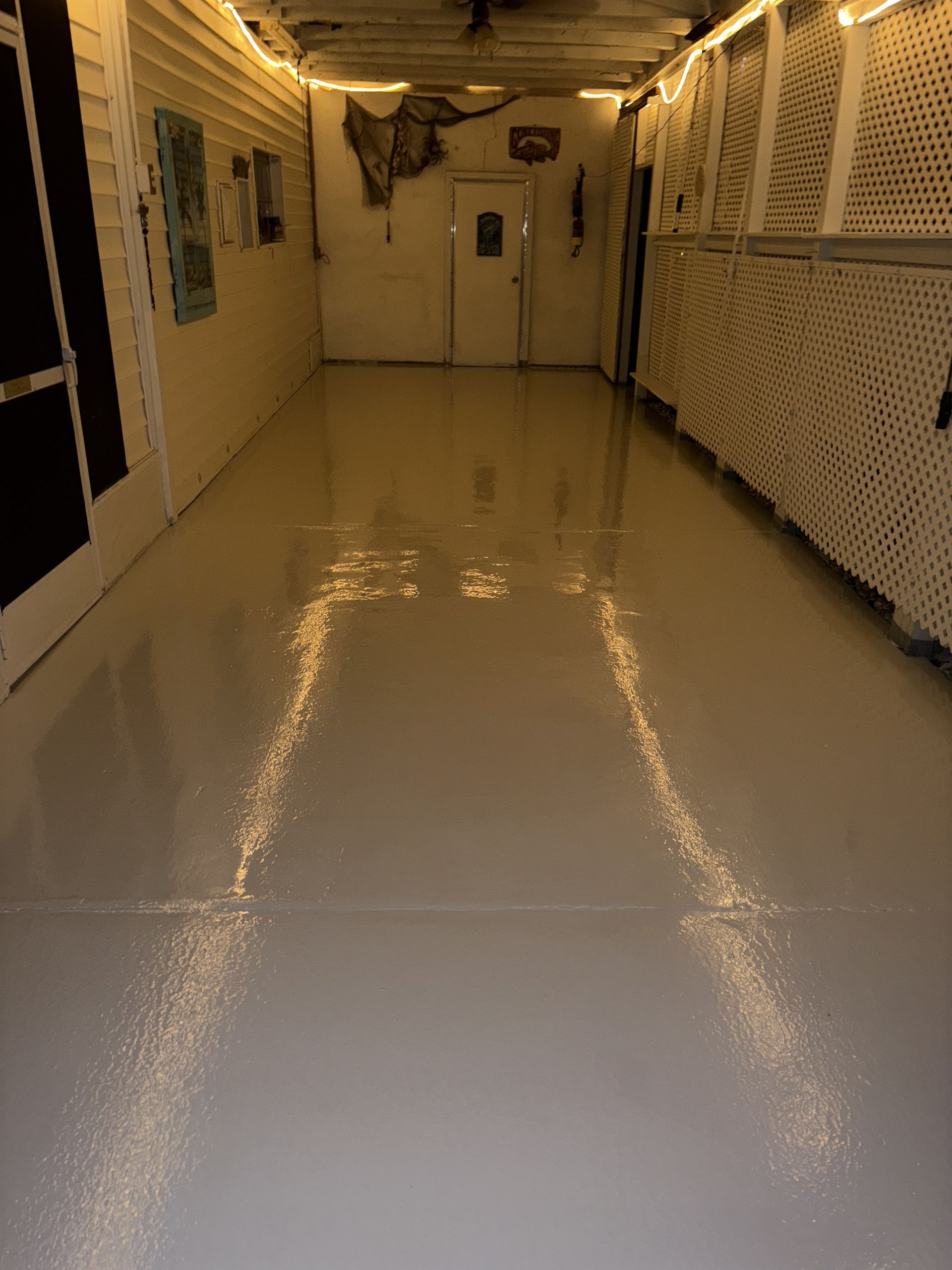 Broom with beige bristles and wooden handle next to a black dustpan on a wooden floor.