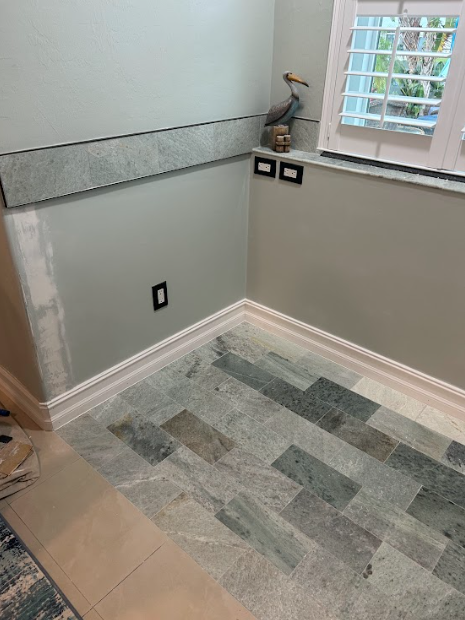 Bathroom corner with green walls, stone tile floor, and a pelican statue.