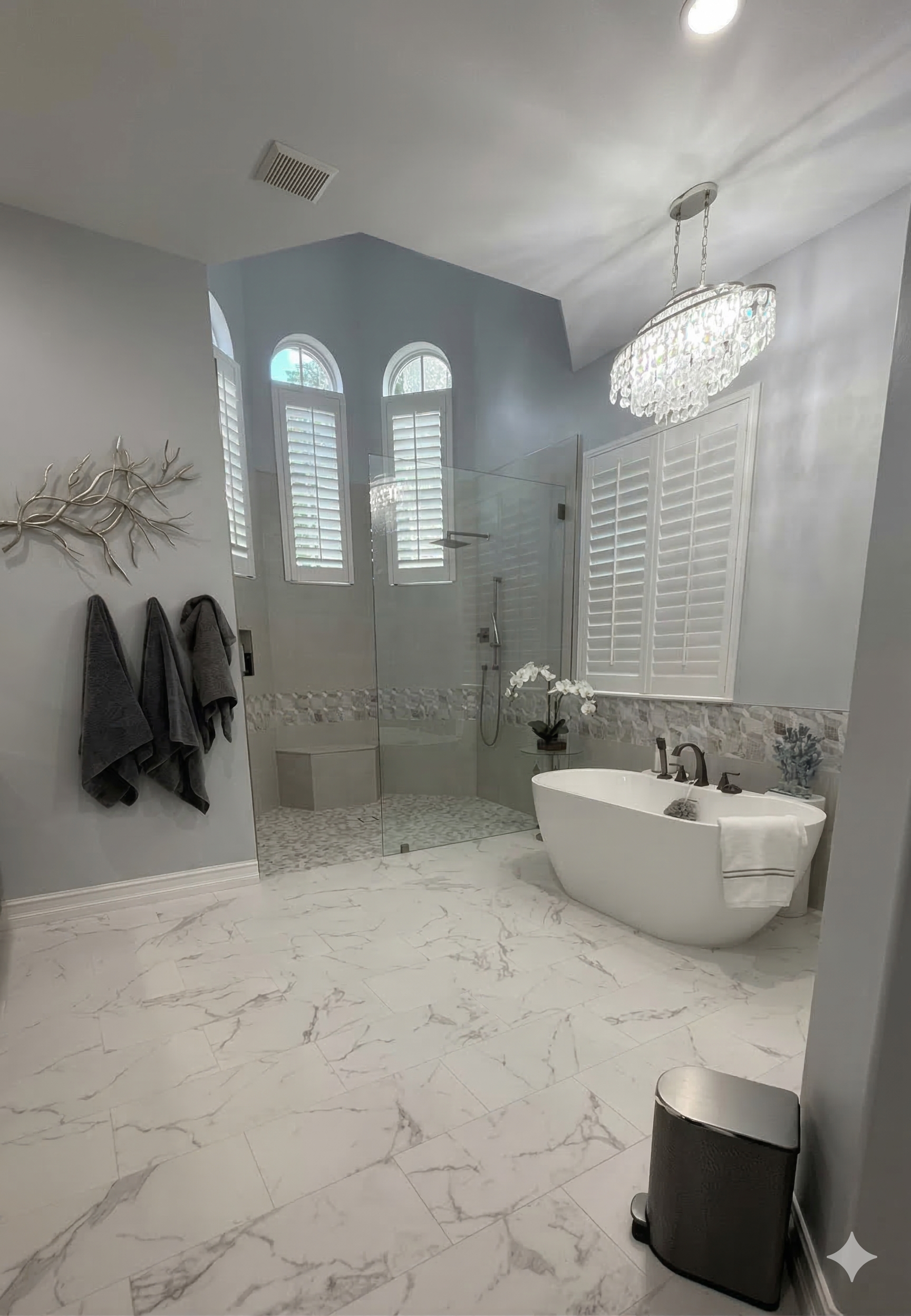 Two vanity mirrors in a bathroom with matching light fixtures over a gray double vanity.