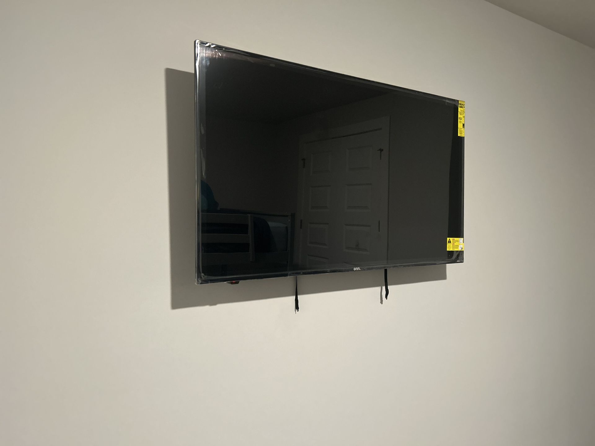 White barn door on a black sliding track; black handle. Mounted on white trim. Gray wall in the background.