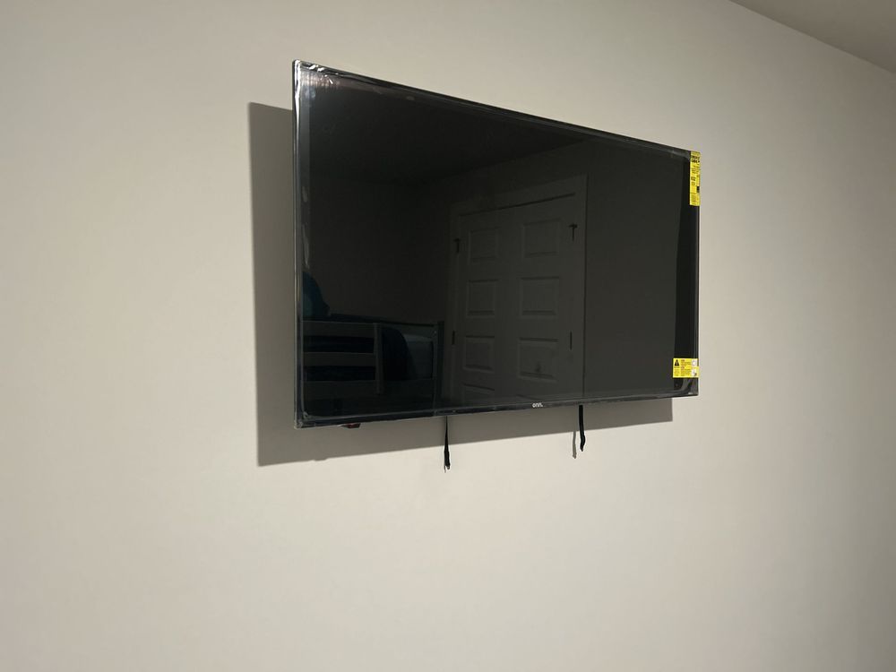 White barn door on a black sliding track; black handle. Mounted on white trim. Gray wall in the background.