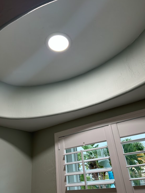 Lighted recessed ceiling and window with shutters.