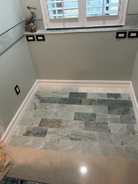 Bathroom with green stone accent wall and light gray walls, white trim, and a window.