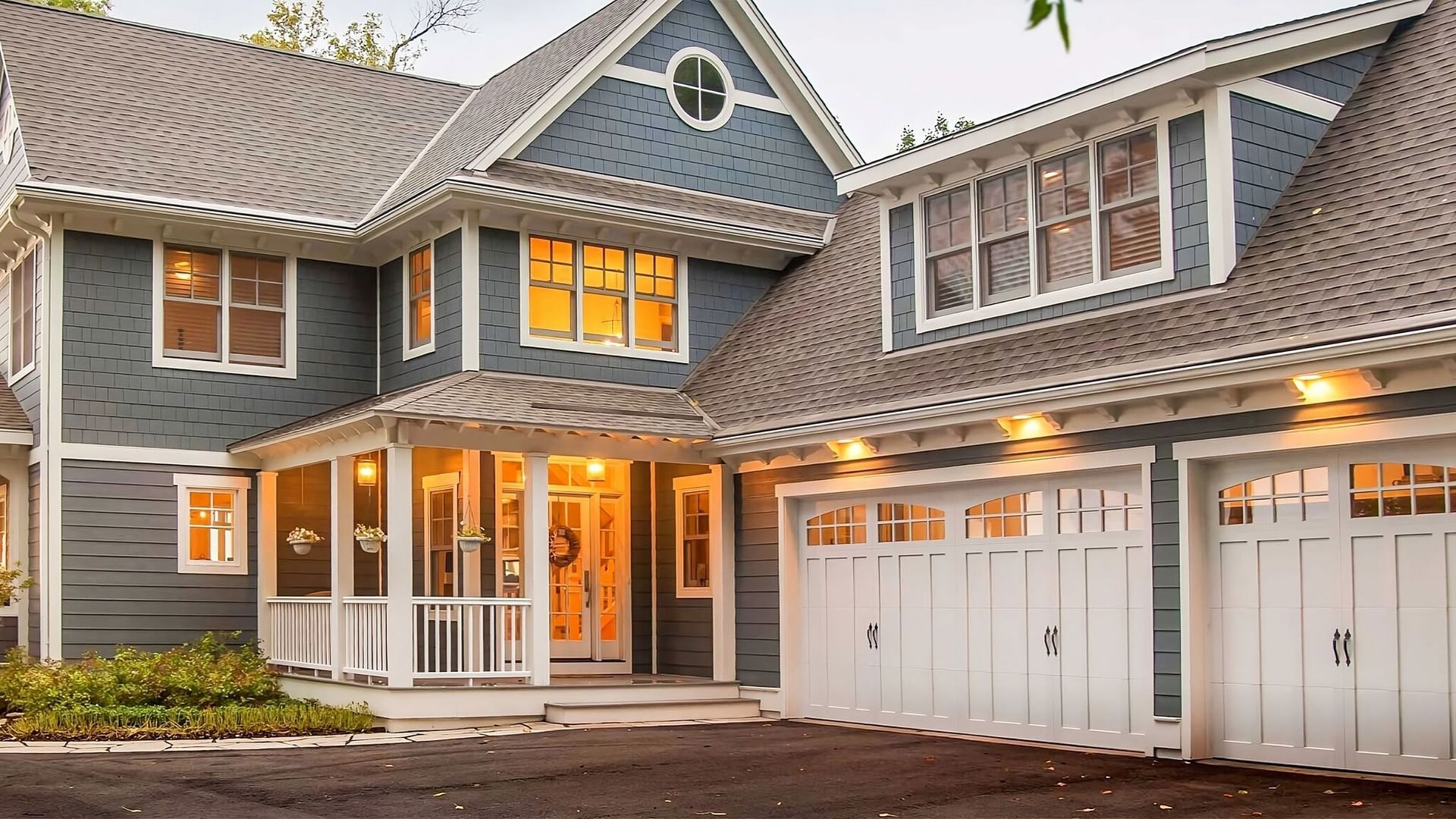 A large blue house with white garage doors and a large porch.