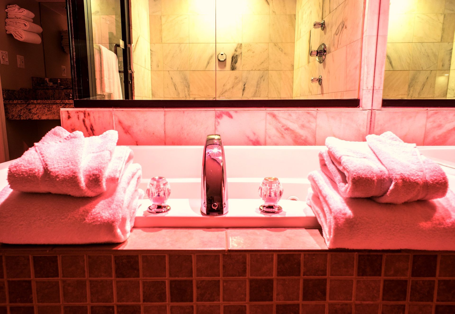 Bathtub with towels and robes, in a bathroom with red lighting.