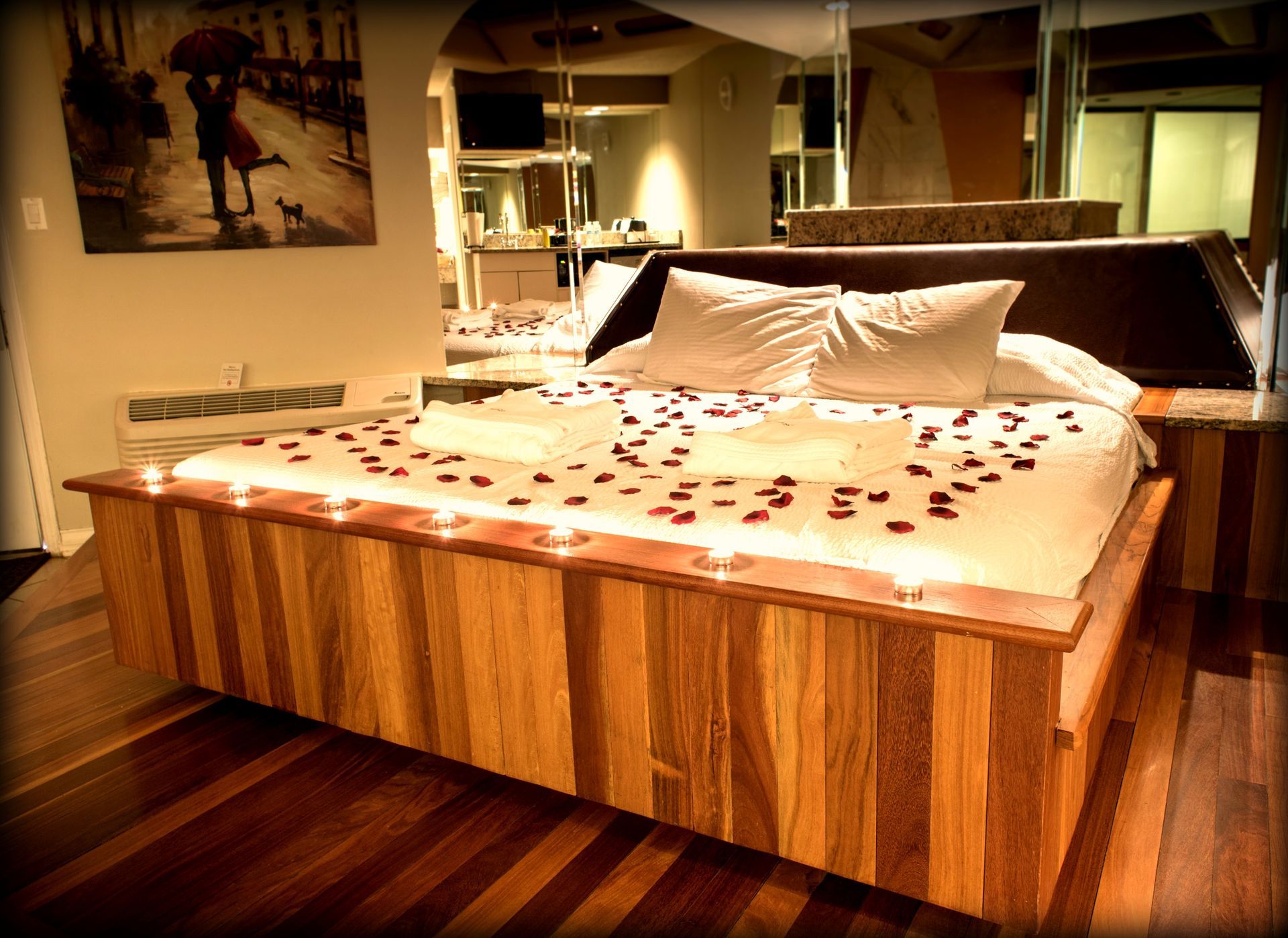 Romantic bedroom with bed, rose petals, and candles.