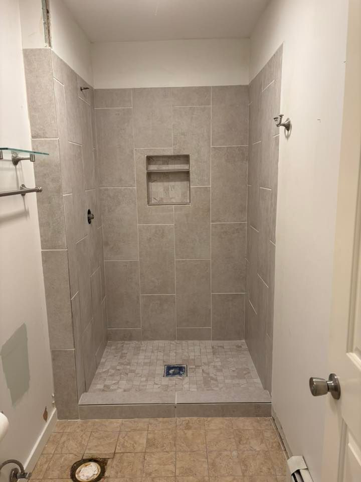 A man is kneeling on the floor applying tile adhesive.