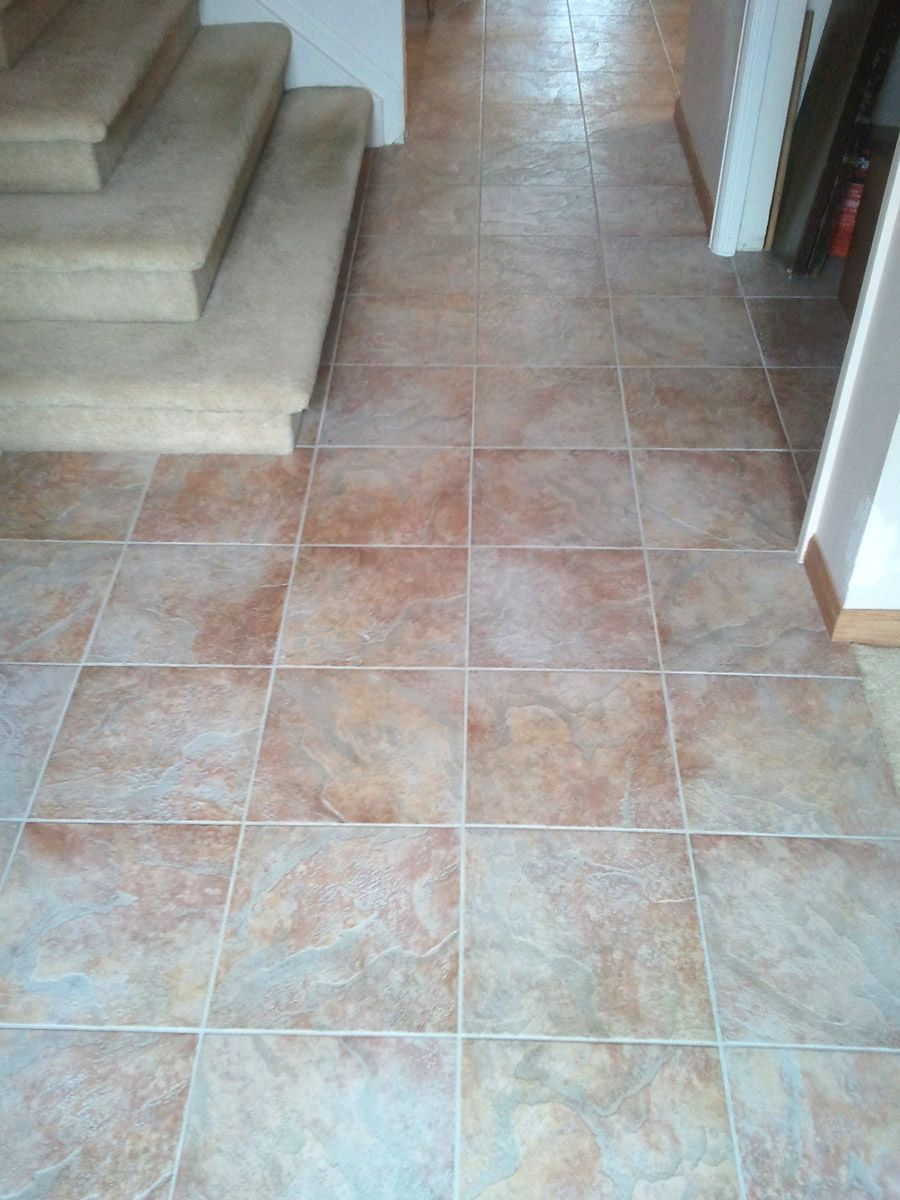 A man is laying tiles on the floor in a living room.