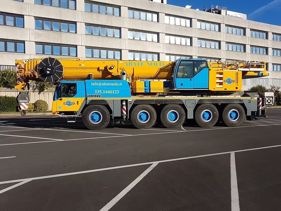 Gru mobile gialla e blu parcheggiata davanti a un edificio.