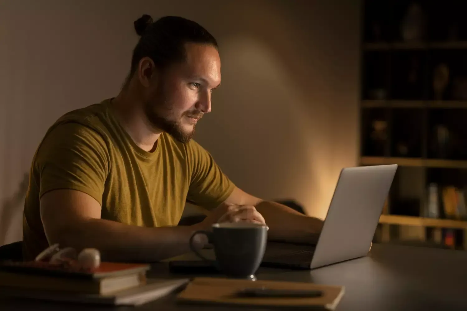 Um homem está sentado à mesa usando um laptop.