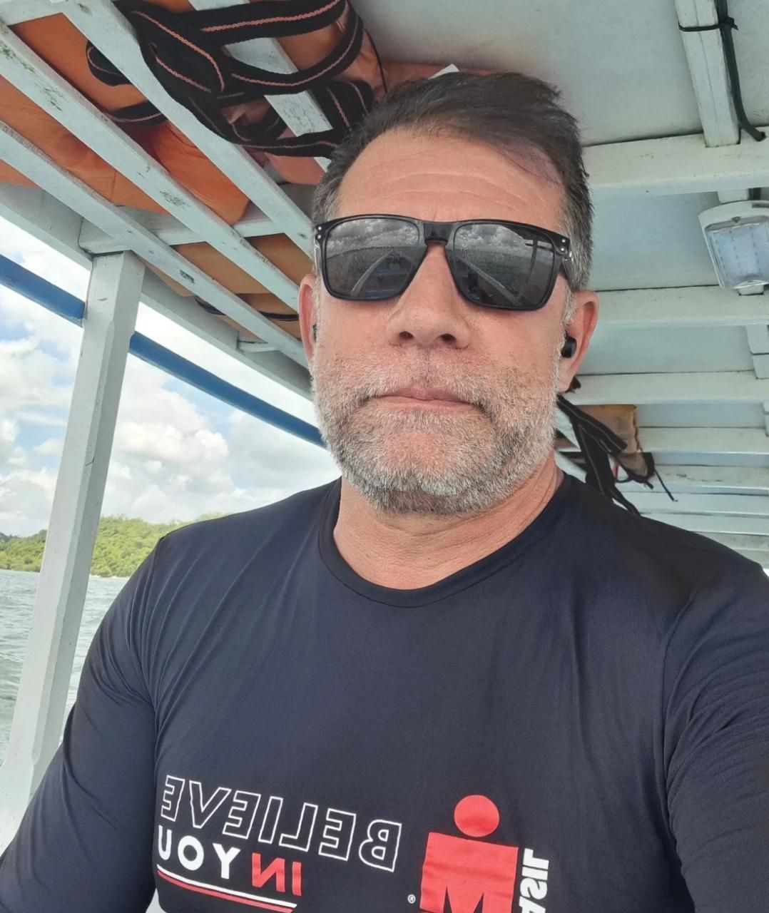 Um homem usando óculos escuros e uma camisa que diz alegria