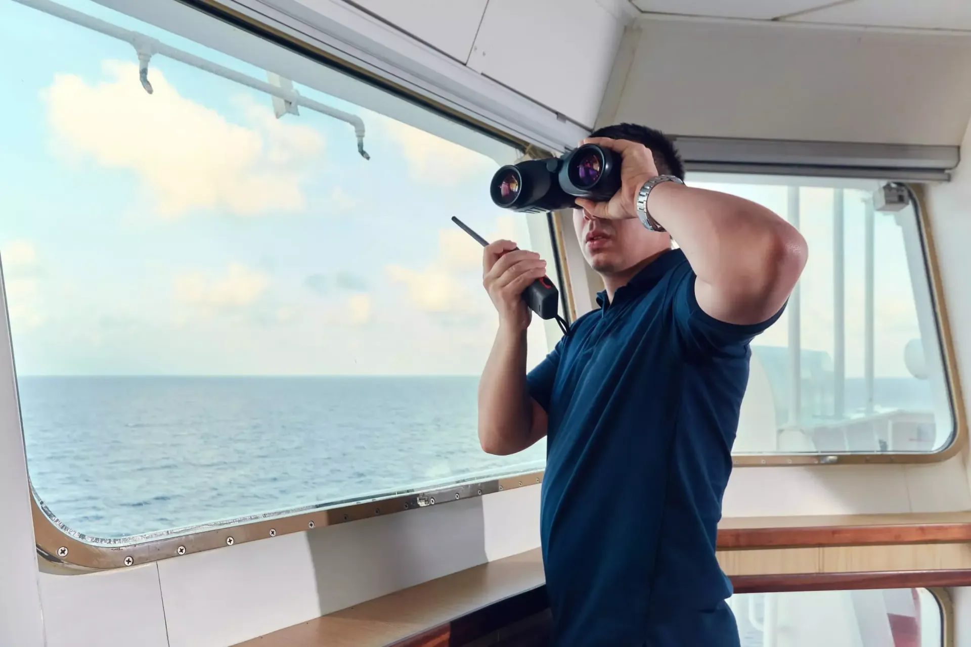 Um homem está olhando por um binóculos em um barco.