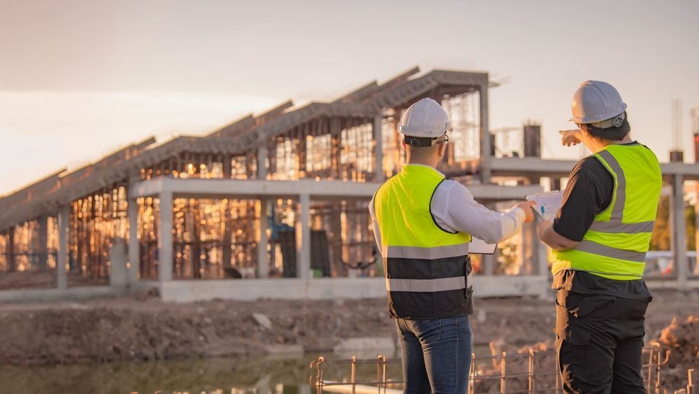 Two construction workers are looking at a blueprint at a construction site.