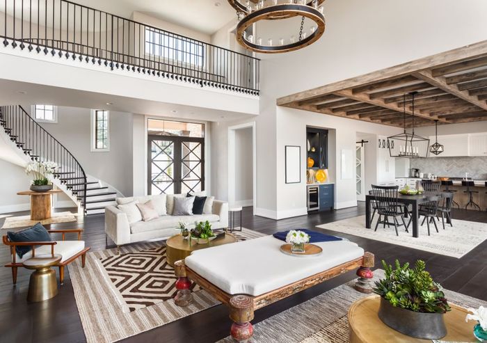 A living room filled with furniture and a staircase in a large house.
