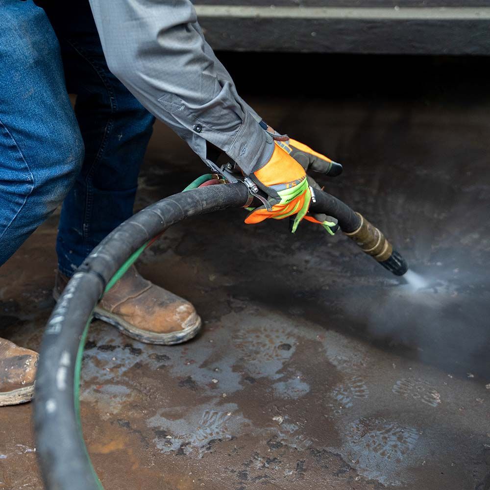A person wearing gloves is using a hose to clean a car