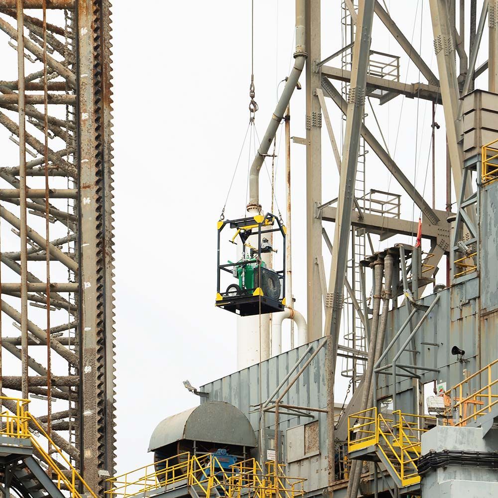 A man in a bucket is being lifted by a crane in a factory.