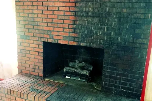 A brick fireplace with logs in it in a living room.