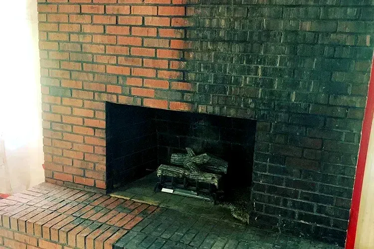 A brick fireplace with logs in it in a living room.