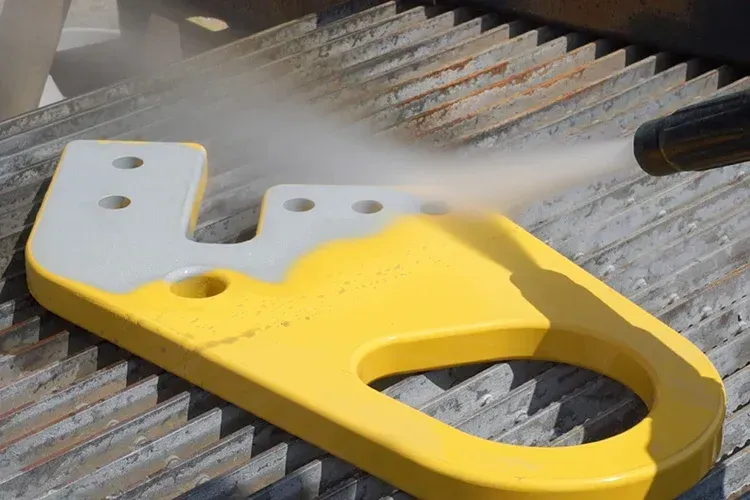 A yellow and white object is being sprayed with a high pressure washer.